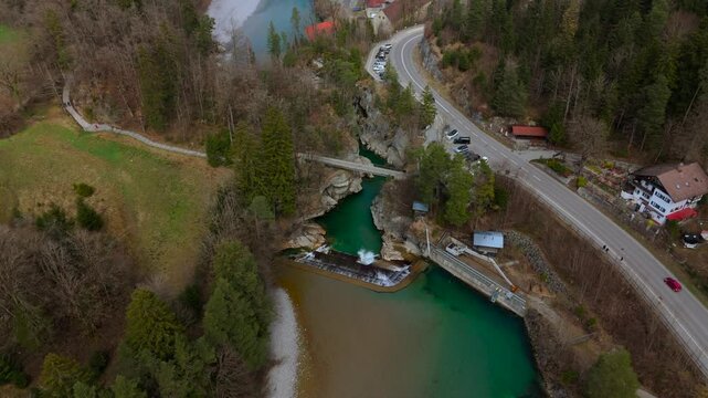 A breathtaking aerial view of Lechfall in Fussen, Germany. The turquoise waters cascade over the dam, surrounded by rugged cliffs and lush forests. A must-visit natural wonder in the Bavarian Alps