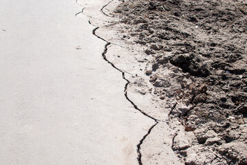cracks on the edge of an asphalt road with dirt

