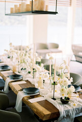 Set festive table with white bouquets of flowers on a narrow fabric and black plates