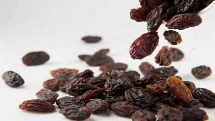 Obraz premium Dried Raisins Falling From Bowl Against White Background