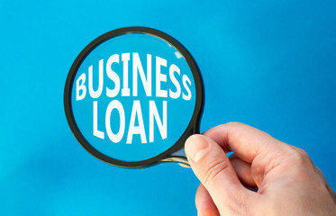 Business loan symbol. Magnifying glass with words Business loan. Beautiful blue background. Businessman hand. Business and Business loan concept. Copy space.