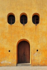 Fototapeta premium Charming facade featuring arched doorway and round windows on textured yellow wall in classic architectural style