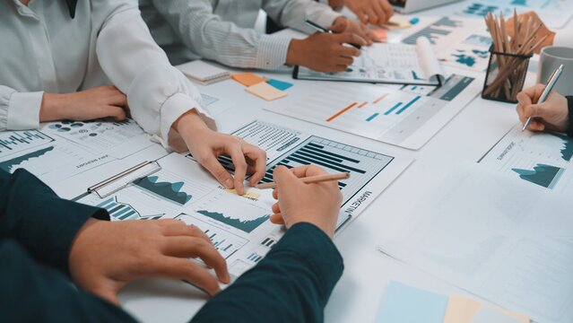 A diverse team engages in a collaborative financial analysis in a modern office. The workspace features charts, graphs, and data documentation, emphasizing teamwork and strategy. SACTR