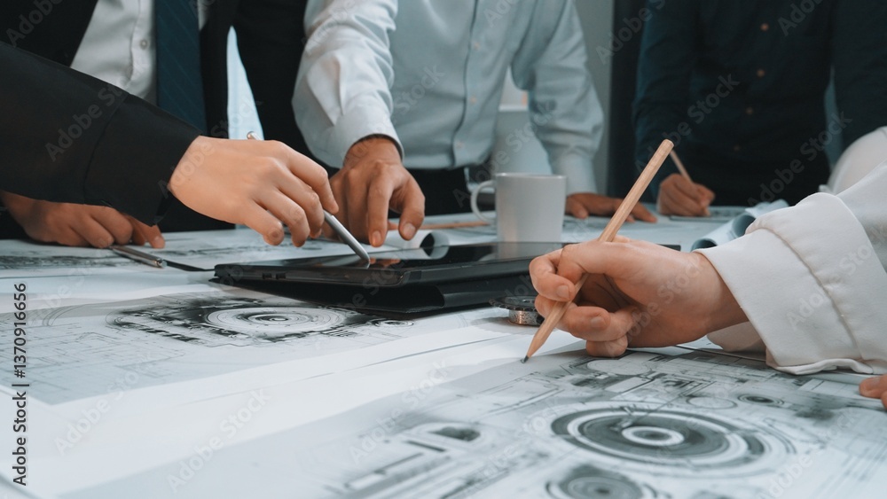Poster hands engaged in a discussion over graphical design plans and technical drawings during a collaborat