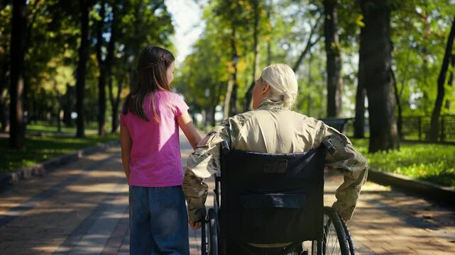 Happy little girl walks beside military mom in wheelchair, family time out