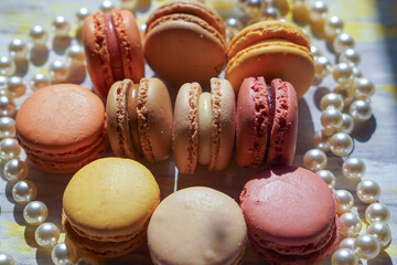 Macaroons of different colors with different flavors and pearl beads. Sweet treats for guests to...