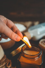 A hand lighting a candle in a cozy baking setup with cinnamon buns, flour, sugar, and eggs on a dark surface, ideal for warm kitchen scenes.