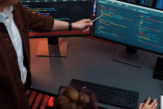 Top view of IT developers discussing with point to intelligent website development coder system running data online two screens information technology at neon light room at modern office. Infobahn.