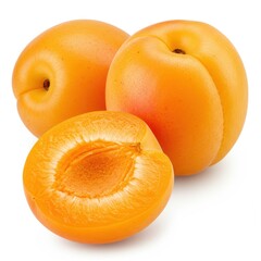Three apricots two whole and one cut in half on a white surface in a still life photograph