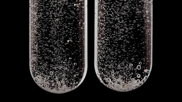 Close up tablet of aspirin, vitamin falls into of water in glass test tube in slow motion on black background. Macro shot of bubbles effervescent. The medicine concept, health care, treatment.FullHD 