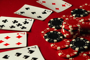 A group of full house or full boat playing cards and poker chips are arranged on a red table, creating an atmosphere of excitement during a friendly gaming evening. Big win in poker