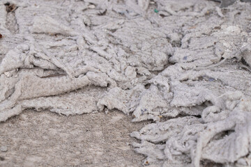 Old torn cotton wool on a chair under the upholstery as a background, torn dirty fabric