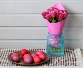 Pink tulips in vase and dyed easter eggs celebrating spring holidays
