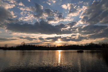 Scenic Landscape of beautiful sunset over lake in spring with cloudy sky in background.