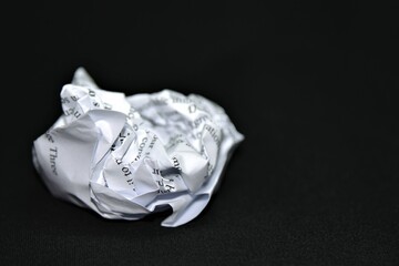 crumpled up piece of paper against a black background