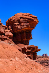Balancing rock at the bottom of a canyon among Layered geological formations of red rocks.