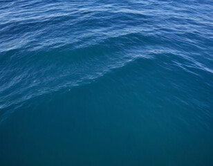 Fototapeta premium Ocean water surface with gentle waves, deep blue tones, sunlight shimmering on the surface, high-detail photography