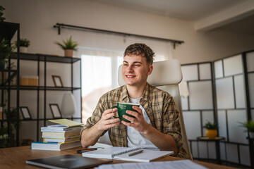 man student study for exam from notes and books while drink coffee