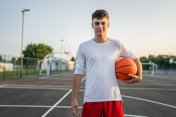 One caucasian teenager stand on basketball court with ball