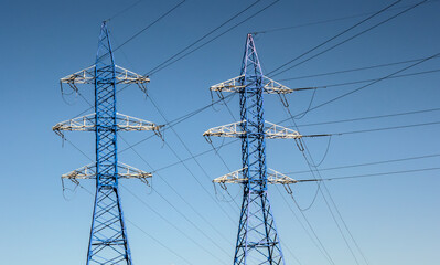 Overhead high voltage power line against blue sky