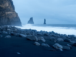 Reynisfjara Beach at dusk with rugged basalt columns and Reynisdrangar sea stacks. The black sand...