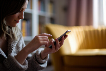Contemplative Young Woman Engaged with Smartphone in Cozy Living Room with Soft Lighting