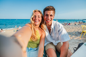 A cheerful couple captures a perfect selfie at the beach, radiating joy and excitement on a beautiful day. The coastline glimmers under the sun as they create lasting memories with laughter and smiles
