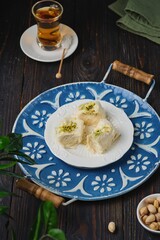 Eastern sweet, pishmaniye or cotton halva with pistachios on a white plate on a dark wooden background. Sweets from around the world.