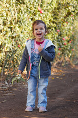 happy cute girl smiling and walking in the garden enjoying the nature at sunny day and green trees