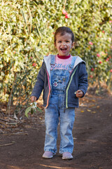 happy cute girl smiling and walking in the garden enjoying the nature at sunny day and green trees