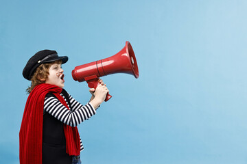 Cute boy in mime costume shouting in megaphone on light blue background, space for text. Surprise...