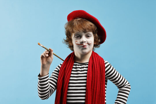 Cute boy in mime costume with brush on light blue background. Surprise party