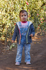happy cute girl smiling and walking in the garden enjoying the nature at sunny day and green trees