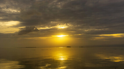 Sunset over calm waters with reflections and dramatic clouds