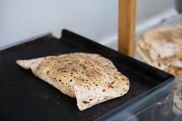 Close-up of folded and grilled gözleme flatbread cooking on a hot griddle at a street food stall in Berlin