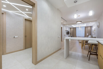 Laconic interior design of the studio apartment. Kitchen area with a white table. A wide passage into the living room.