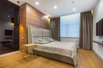 Stylish bedroom interior. The walls are decorated with various textures, wood and black glass. A bed with a high headboard.