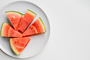 Fresh watermelon slices on white plate against minimalist background