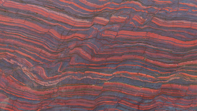 Close up cut red stone with natural patterns and texture. Banded iron ore. Mineral structure, geological layers, natural background for design.