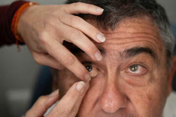 Ocularist placing ocular prosthesis in patient's eye socket