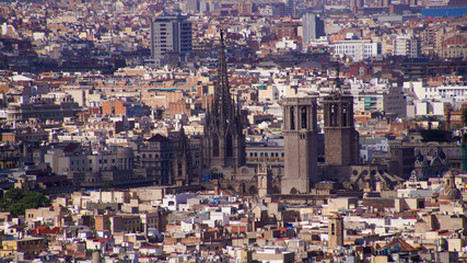 Panoramic view of Barcelona with the Gothic Cathedral of the Holy Cross and Saint Eulalia standing out among dense urban rooftops. Historic architecture surrounded by modern cityscape