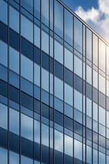 Obraz premium Modern glass building reflecting sunlight and clouds in an urban setting