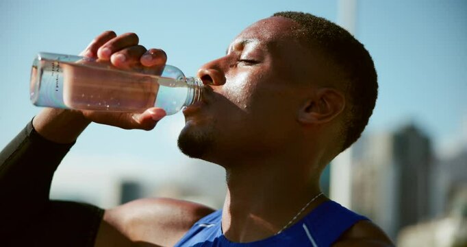 Black man, runner and drinking water in city on break, training and tired with hydration for wellness in summer. Person, bottle and liquid for workout, exercise and fitness for marathon in Cape Town