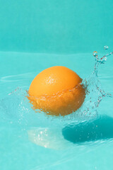 Single Orange Fruit Floating in Water Turquoise Background
