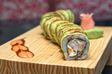 Fish and avocado sushi rolls served on a wooden board accompanied by wasabi, Japanese food