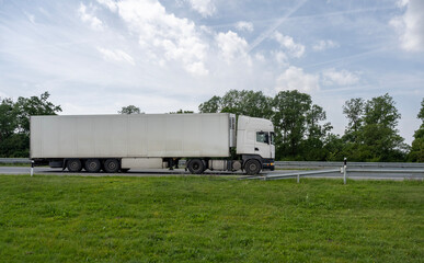 White transportation truck on a countryside highway under a dramatic sunset sky.