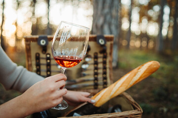 Close up of glass of wine in front of picnic bag in the forest