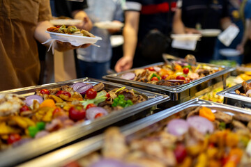 Festive buffet spread featuring a variety of grilled meats and vibrant vegetables in a lively dining setting
