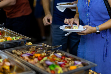 Guests enjoying a buffet spread with a variety of dishes at a lively social gathering in the evening