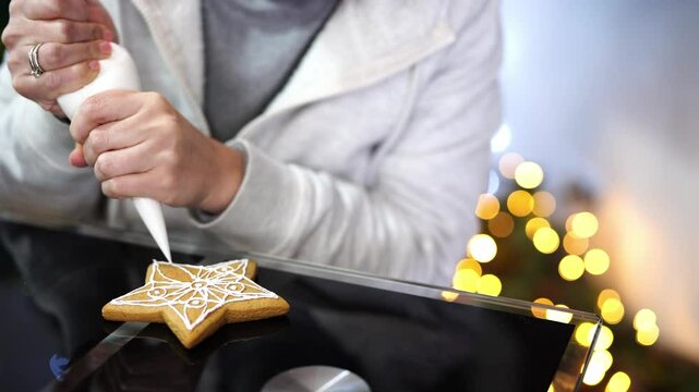 Confectioner draws icing patterns with pastry bag on Christmas cookies